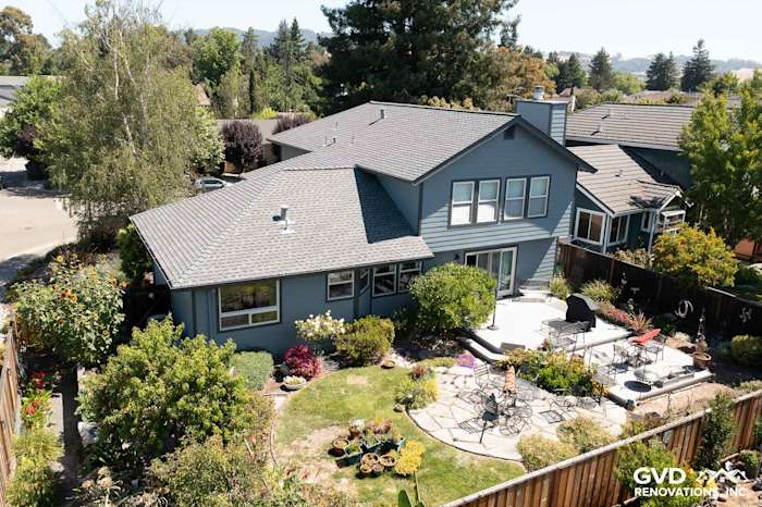 Home exterior showcasing new Boothbay Blue James Hardie siding and Milgard windows, surrounded by landscaped garden