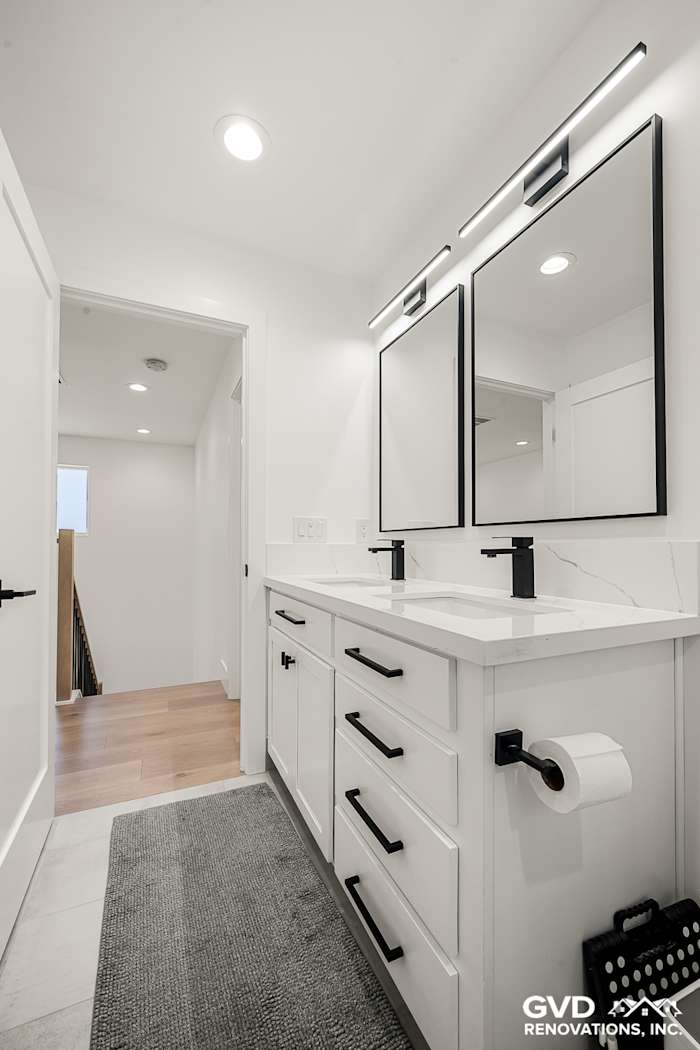 Bright modern bathroom with dual vanities, black fixtures, and large frameless mirrors in Antelope, CA remodel