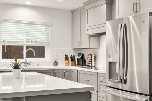 Modern kitchen remodel featuring gray cabinetry, quartz countertops, stainless steel appliances, and luxury vinyl plank