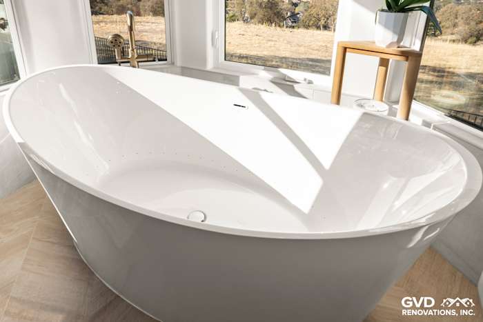 Freestanding BainUltra air jet tub with sleek design, surrounded by windows in luxurious El Dorado Hills bathroom