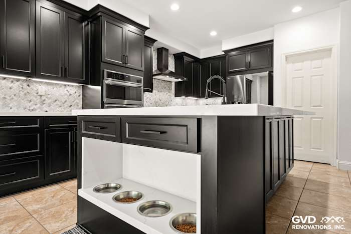 Modern kitchen remodel in Roseville, showcasing black Waypoint cabinets, MSI countertops, and a built-in pet feeding station