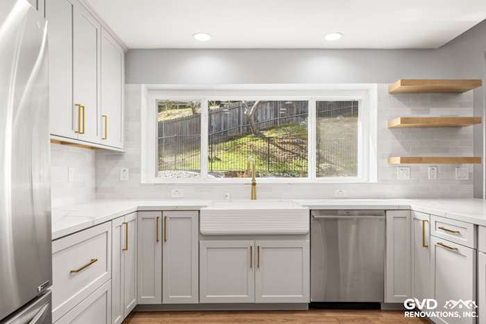 Modern kitchen remodel featuring custom gray cabinetry, quartz countertops, and a large farmhouse sink with gold faucet