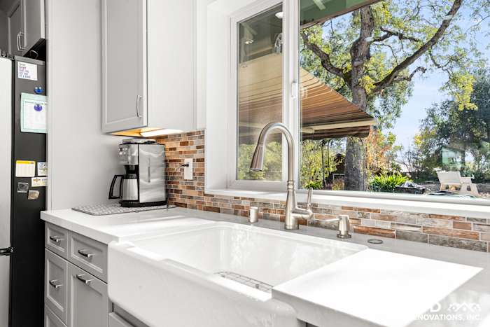 Modern kitchen sink with white farmhouse sink, gray cabinetry, and mosaic backsplash in Greenwood, CA remodel
