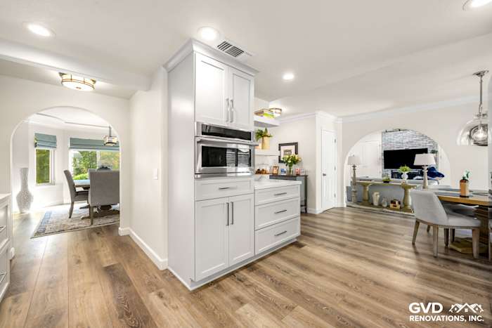 Modern kitchen in Rocklin featuring white cabinets, quartz countertops, and hardwood flooring with dining area visible