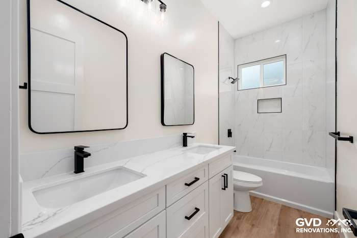Modern Paradise bathroom featuring dual sinks, white cabinetry, marble-like tiles, and black fixtures