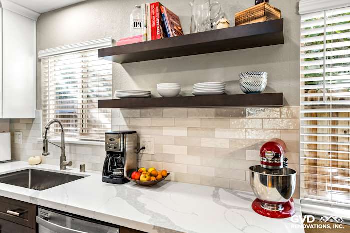 Modern kitchen with white marble countertops, floating dark wood shelves, and sleek appliances in Davis, CA