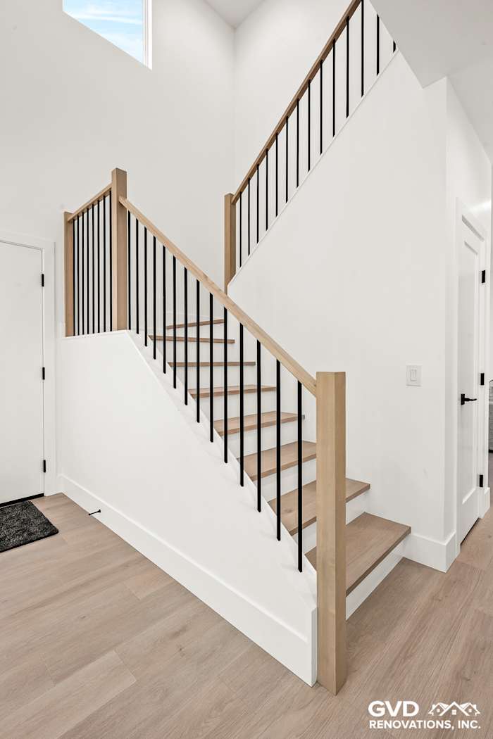 Modern staircase with wooden steps and black railings, featuring a bright, airy design in Antelope home renovation