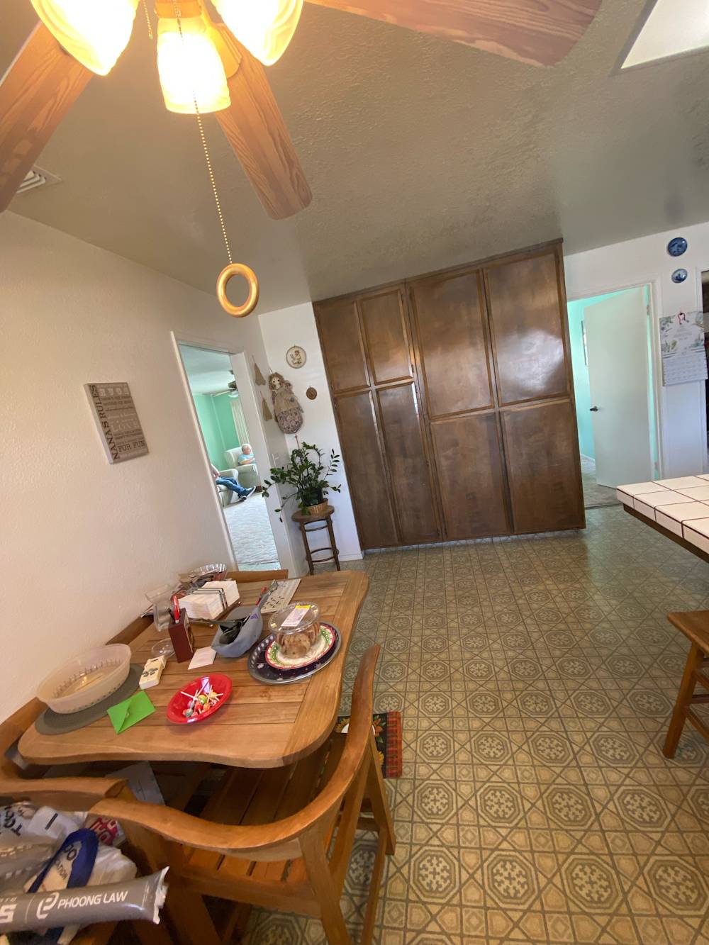 Outdated kitchen with wood cabinetry, patterned linoleum flooring, and dining table in Sacramento home