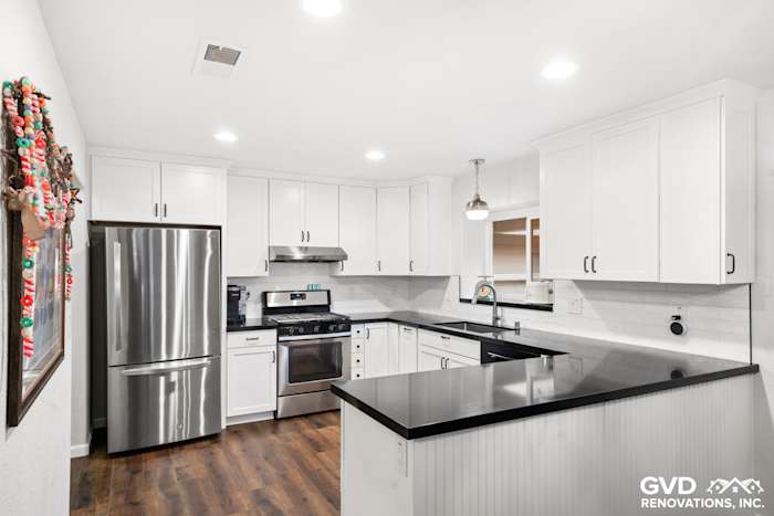 Modern kitchen featuring sleek white cabinetry, black countertops, and stainless steel appliances