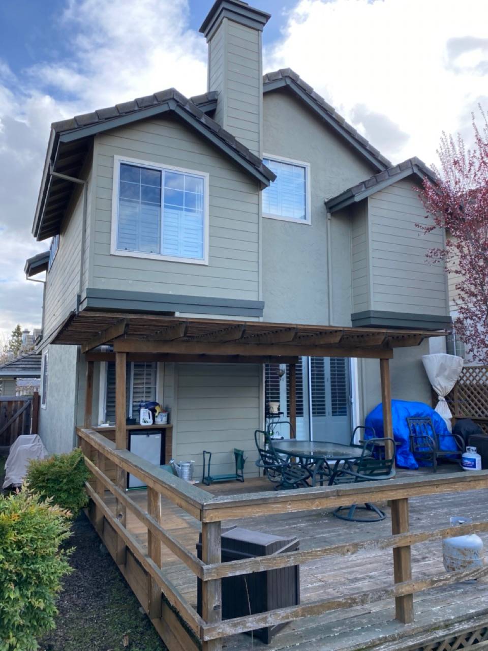 Wood deck with seating, green exterior, and chimney, Sacramento home needing a remodel
