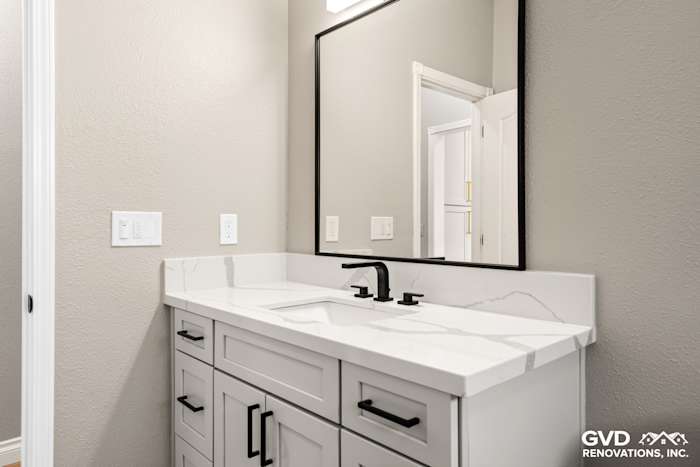 Modern guest bathroom featuring a sleek gray vanity, quartz countertop, matte black fixtures, and large mirror