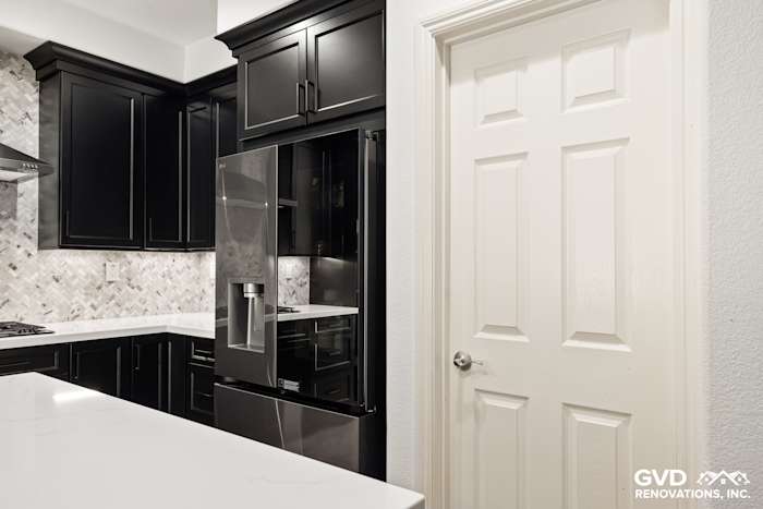 Modern kitchen in Roseville with black Waypoint cabinets, sleek MSI countertops, and built-in refrigerator