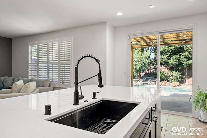 Modern kitchen with elegant MSI countertops, black faucet, and natural light from sliding doors