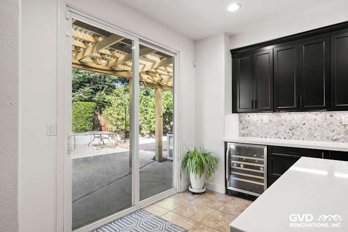 Modern kitchen with black Waypoint cabinets, MSI backsplash, and sliding glass door access to patio
