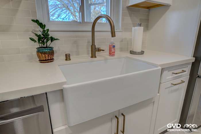 Farmhouse sink with gold faucet, white quartz countertop, and backsplash in renovated Fair Oaks kitchen