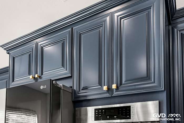 Navy blue kitchen cabinetry with elegant molding and gold hardware, featuring modern appliances in Sacramento remodel