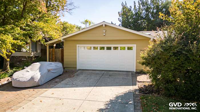 Home exterior with new James Hardie siding, featuring soft yellow color and garage with white door