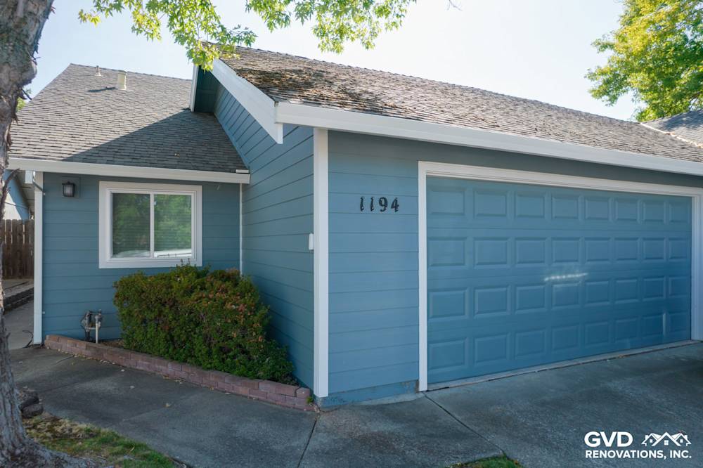 Updated home exterior featuring fresh blue siding and a new garage door