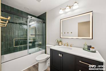 Modern Folsom bathroom with dark cabinetry, green tiled walls, glass shower, and stylish lighting