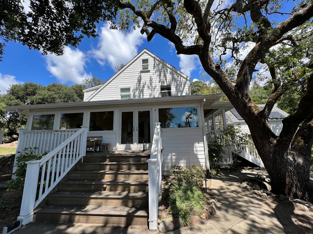 Charming home exterior in Deer Park with wooden steps and large windows under a bright blue sky