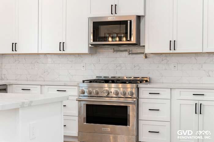 Modern kitchen featuring a stainless steel range, white cabinets, and marble backsplash in Paradise, CA