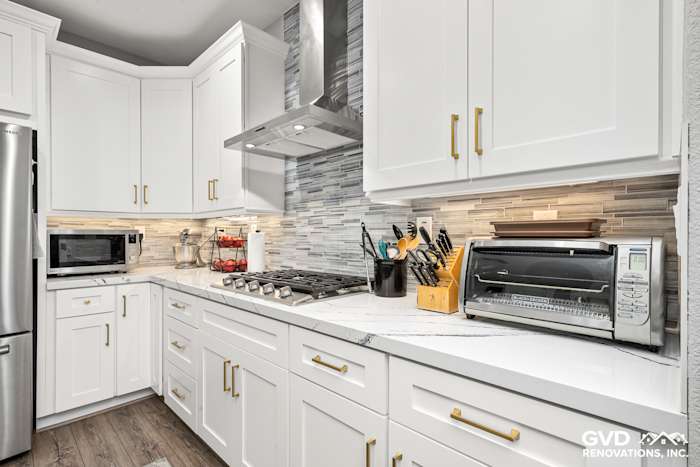 Bright kitchen featuring white custom cabinets, Cambria countertops, and modern backsplash tiles in Roseville remodel