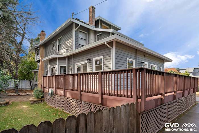 Vinyl siding renovation of a home in Dixon featuring grey siding and a wooden deck with a fenced yard