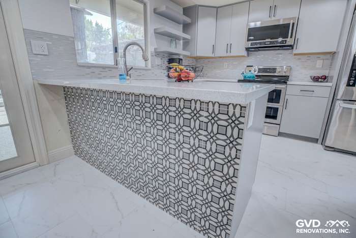 Modern kitchen remodel featuring a geometric backsplash, quartz countertop, stainless steel appliances, and marble flooring