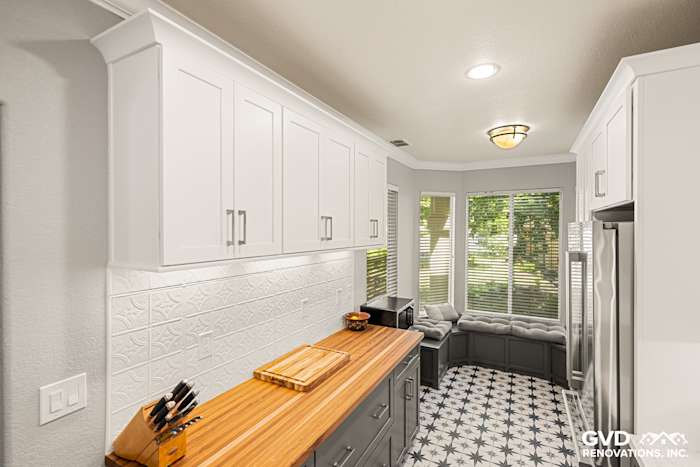 Modern kitchen with white cabinets, decorative backsplash, gray island, and cozy window seat in Folsom, CA