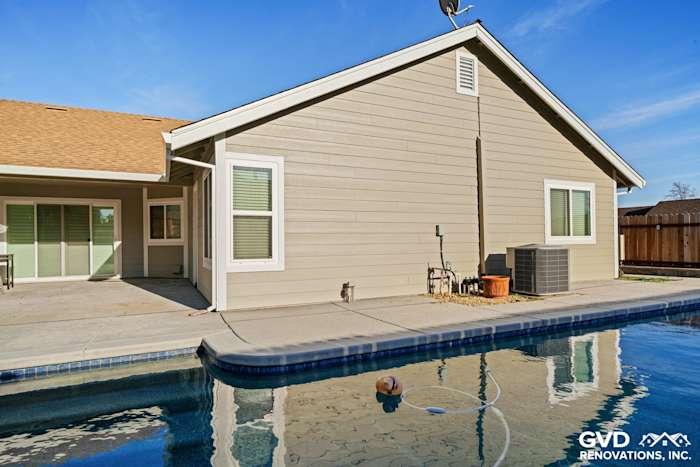 Monterey Taupe HardiePlank siding on a home exterior with Arctic White trim, reflecting in a pool