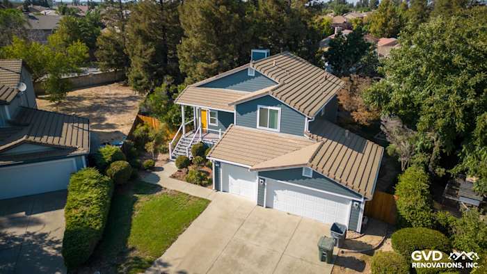 Updated home exterior in Dixon with new blue siding, brown roof, and landscaped yard