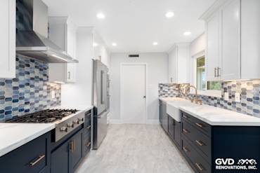 Modern kitchen remodel featuring navy blue cabinets, white countertops, and blue hexagonal backsplash tiles