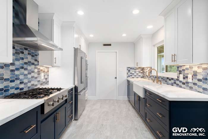 Modern kitchen remodel featuring navy blue cabinets, white countertops, and blue hexagonal backsplash tiles