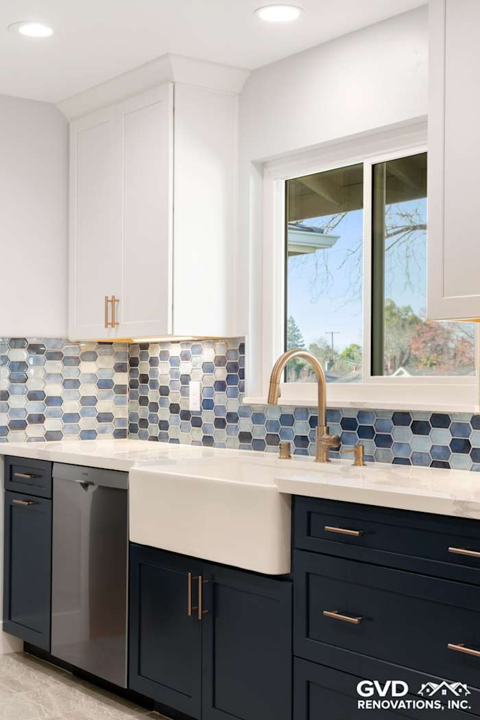 Modern kitchen with navy blue cabinets, white sink, and blue hexagon backsplash in Sacramento remodel
