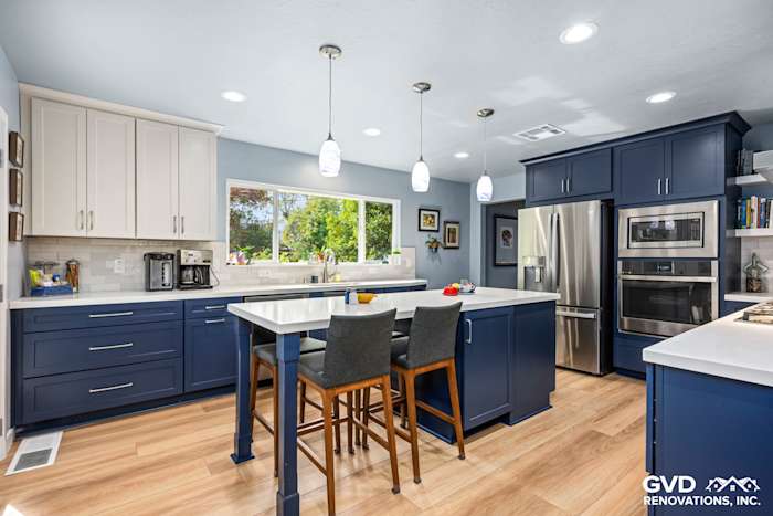 Modern kitchen remodel featuring navy blue cabinetry, white countertops, and an open layout with a large island and pendant