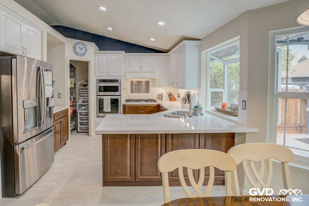 Modern kitchen with white cabinets, quartz countertops, stainless steel appliances, and bright space