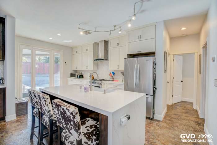 Modern kitchen remodel in Roseville featuring white cabinets, quartz island, and stylish bar stools