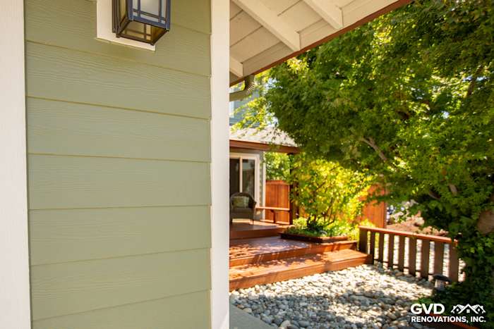 Newly installed James Hardie fiber cement siding in light green, accented by modern lantern and landscaped patio