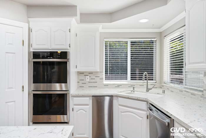 Modern kitchen with white cabinetry, quartz countertops, stainless steel appliances, and mosaic backsplash in Fair Oaks, CA
