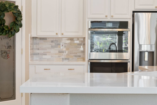 Bright Sacramento kitchen with white cabinets, quartz island, stainless steel appliances, and modern fixtures
