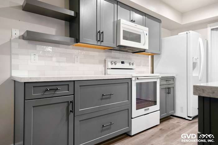 Modern kitchen remodel with gray cabinets, quartz countertop, white appliances, and subway tile backsplash