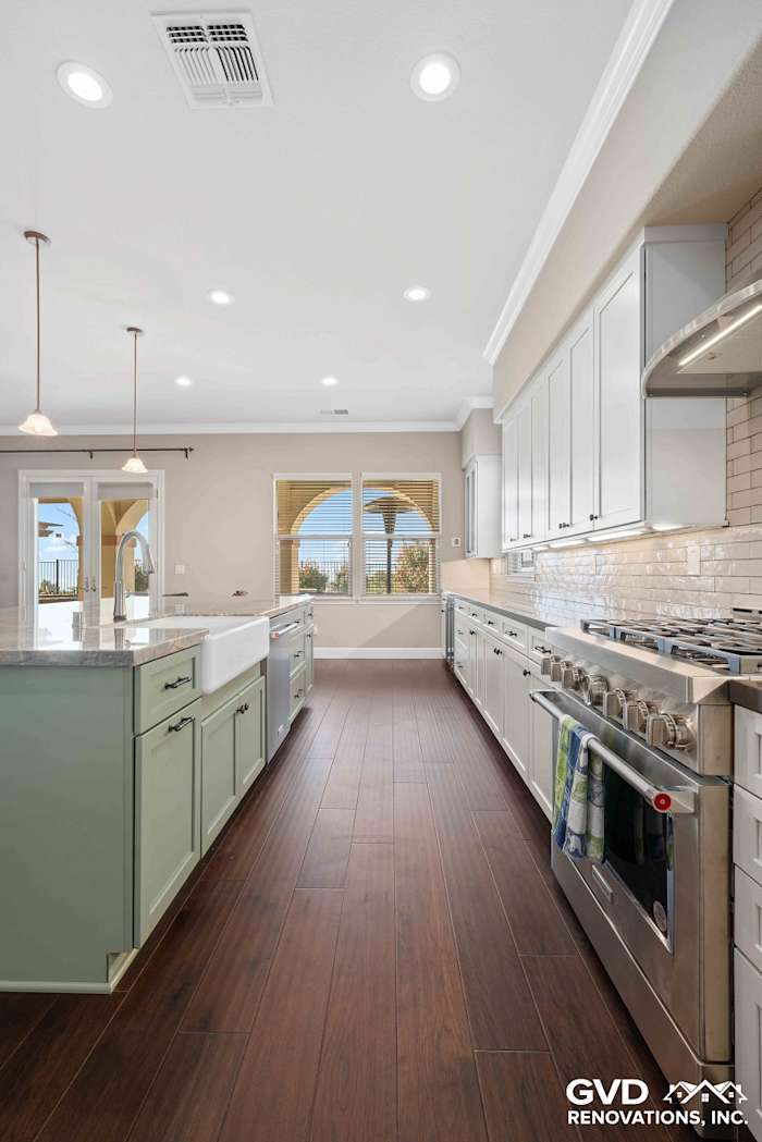 Bright El Dorado Hills kitchen featuring light green cabinets, white subway tile, and dark wood flooring