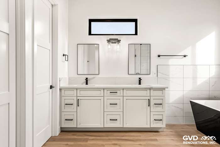 Modern bathroom with white cabinetry, dual mirrors, and a black bathtub in Paradise, CA