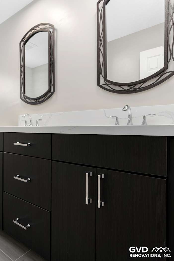 Modern bathroom remodel in Rocklin with dark cabinetry, sleek silver hardware, and dual mirrors above a white vanity
