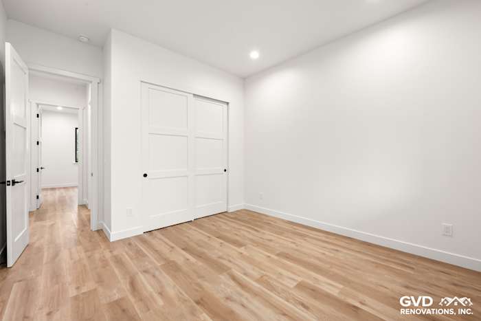 Modern bedroom with light wood flooring, white walls, and double sliding closet doors in new construction home