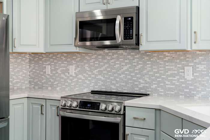 Modern kitchen with light blue cabinets, quartz countertops, and a mosaic tile backsplash in Cameron Park