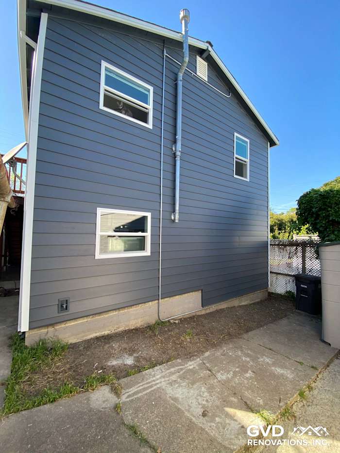 Updated home exterior with new gray CraneBoard vinyl siding, Anlin windows, and clear landscaping in Rio Vista