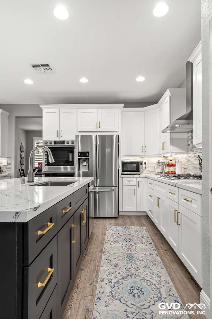 Modern kitchen in Roseville, featuring black and white custom cabinets, Cambria countertops, and elegant lighting