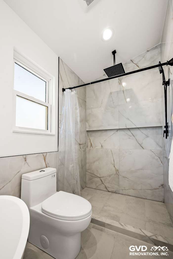 Modern bathroom shower with marble walls, sleek glass door, and contemporary toilet in Antelope, CA remodel