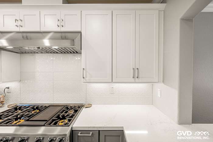 Modern kitchen featuring white cabinetry, quartz countertop, stainless steel range, and textured backsplash in Folsom, CA